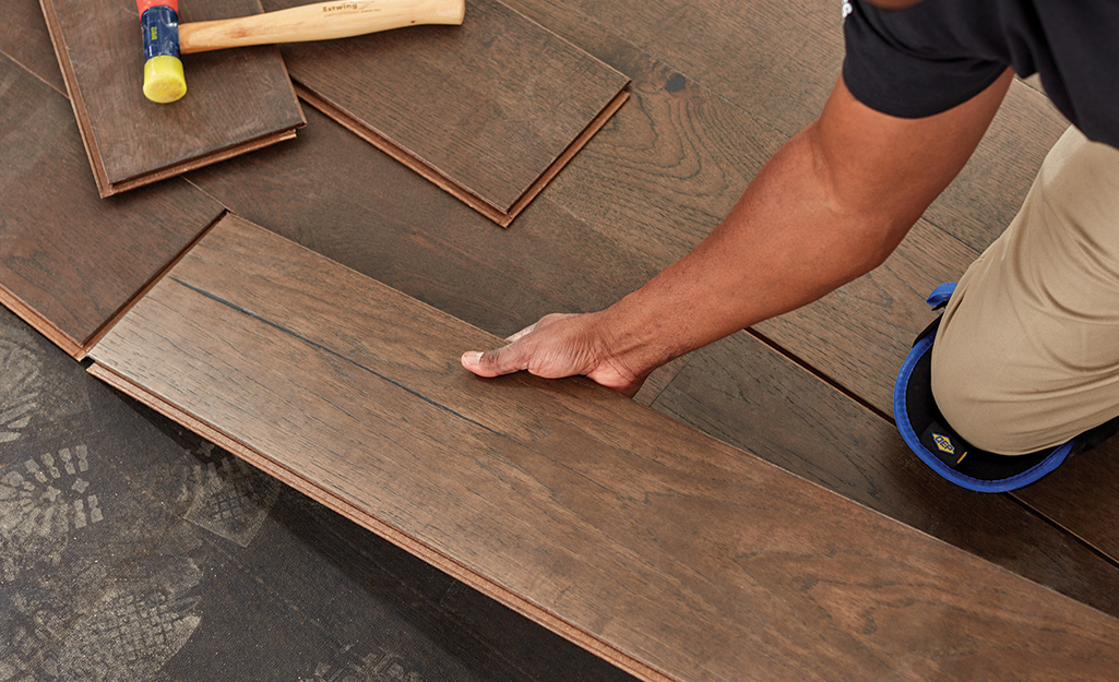 A person installing hardwood flooring planks during a renovation project.