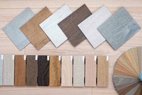 Collection of flooring samples including wood and tile textures arranged on a wooden surface